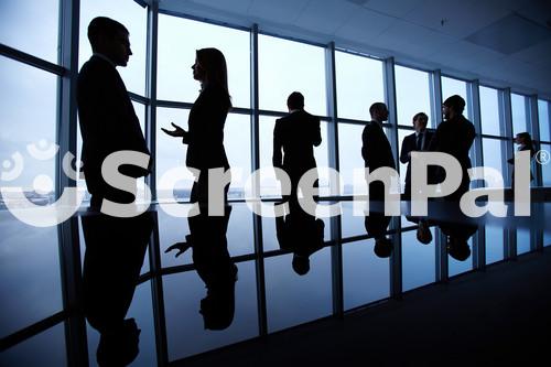 Group Of Colleagues Standing Against Window In Office And Speaking